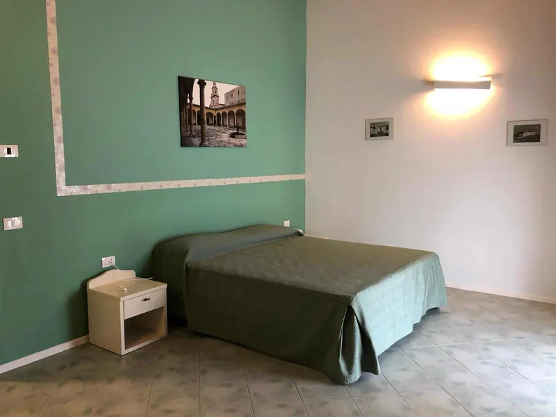 Camera con parete verde e letto matrimoniale